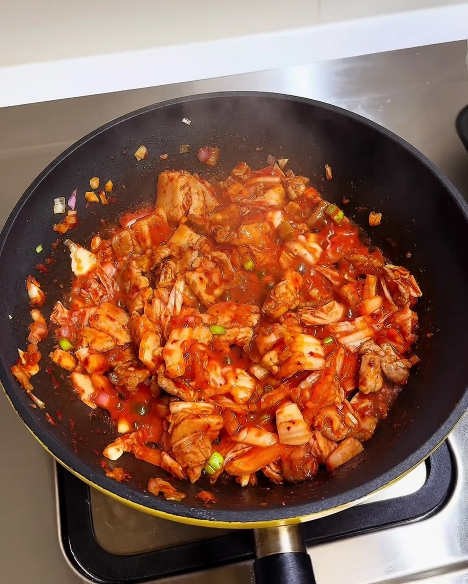 Riso bianco cotto aggiunto alla padella contenente kimchi e pancetta saltati.