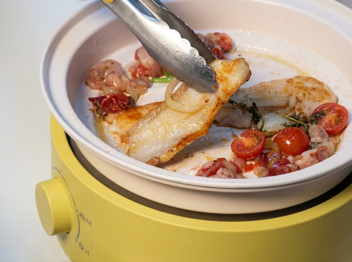 Fette di pancetta di maiale, manzo e cipolle che sfrigolano su una griglia elettrica gialla.