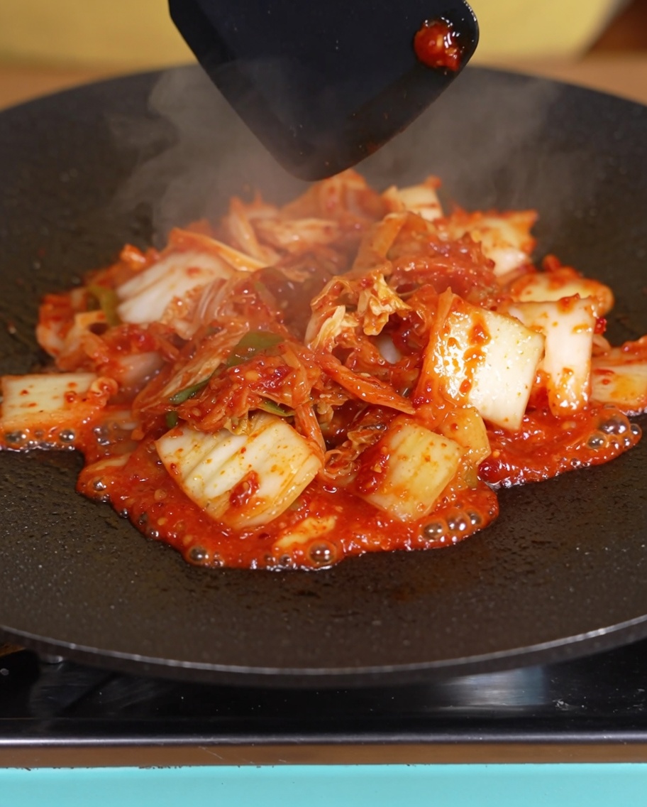 Il kimchi in cottura nella padella con una evidente riduzione del liquido.