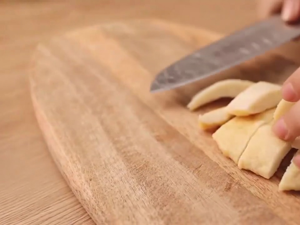 Primo piano di un coltello che pratica un taglio a forma di I su un wurstel vegetariano.