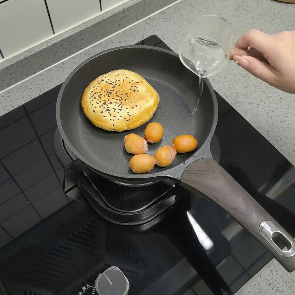 Salsicce piccole in padella accanto al panino, mentre viene versata una piccola quantità dacqua.