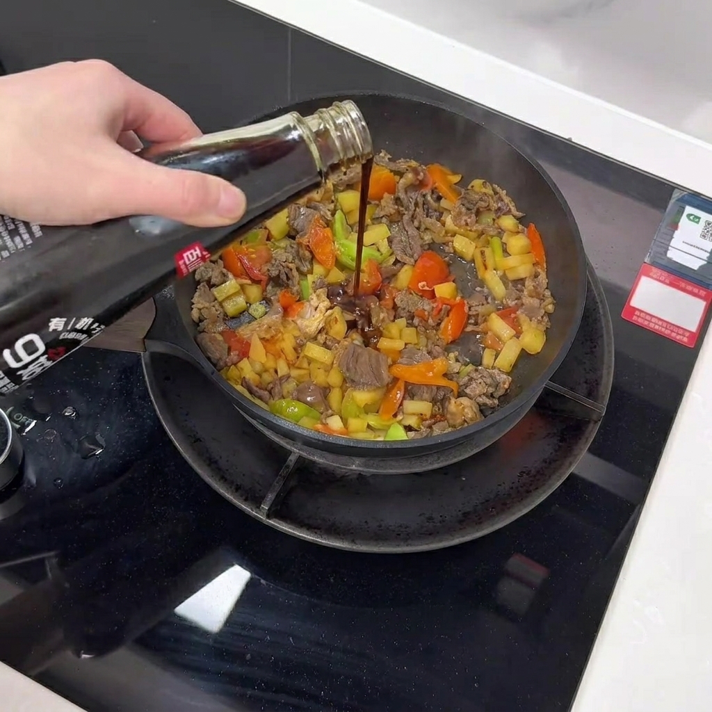 Salsa scura ai funghi versata da una bottiglia in una padella con manzo, patate e verdure.