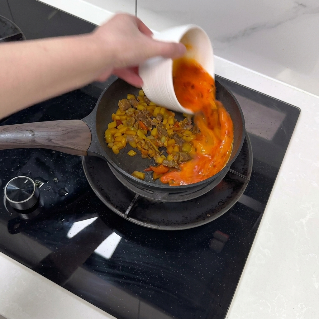 Composto di uova e peperoncino versato in padella sugli ingredienti.