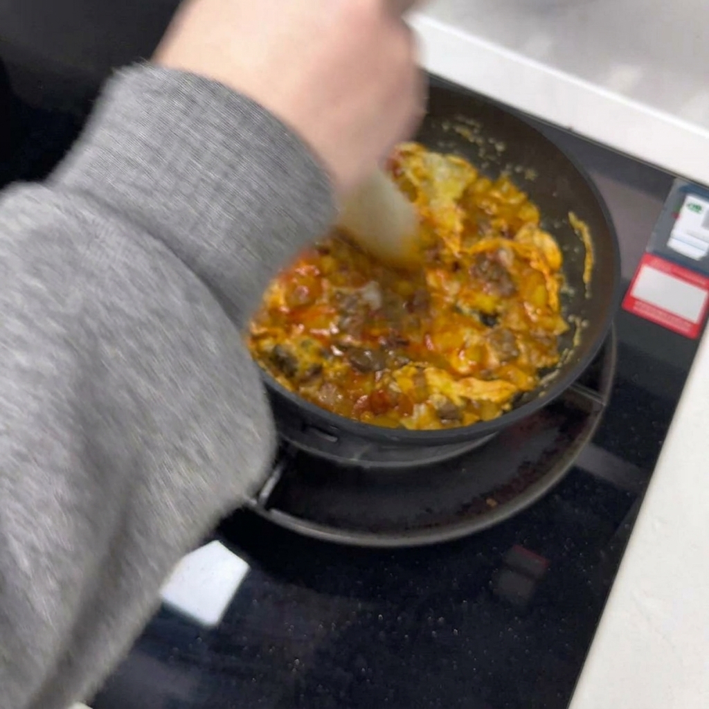 Una spatola che divide la frittata in due metà dentro la padella.