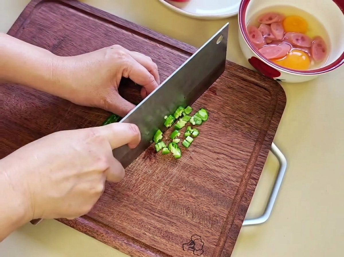 Pezzetti di peperoncino verde finemente tritati su un tagliere di legno.