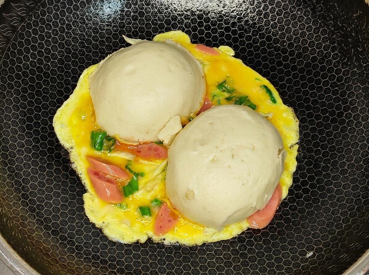 Lomelette capovolta con la parte delluovo cotta rivolta verso lalto e i panini sotto nel wok.