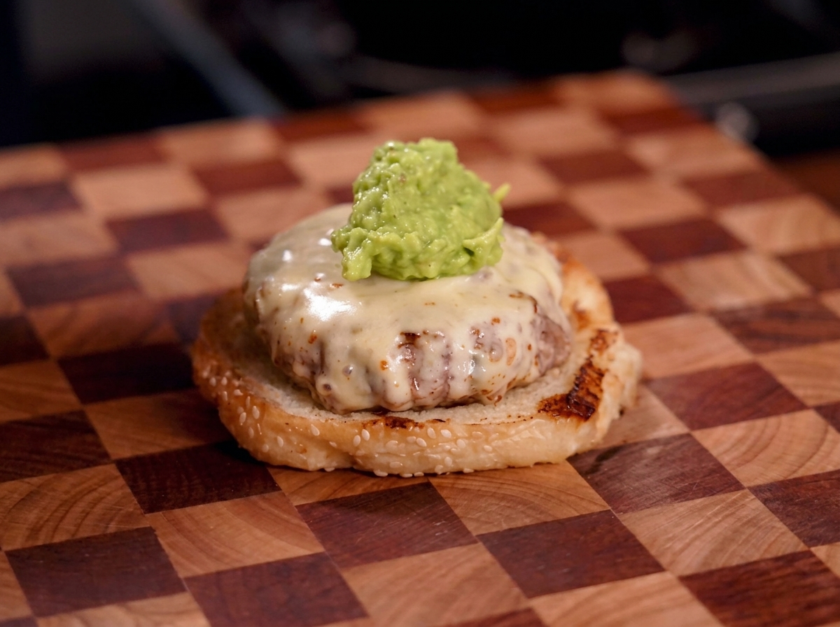Una generosa cucchiaiata di guacamole verde e corposo sopra un patty coperto di formaggio fuso.