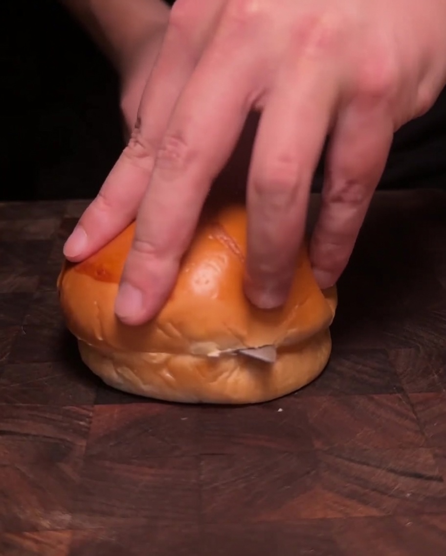 Due metà di un panino da hamburger capovolte in una padella, a tostare nel burro fuso fino a doratura.