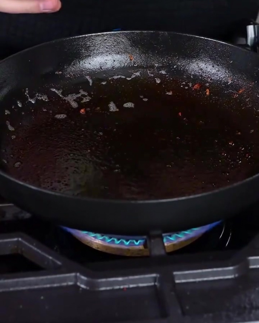 Cipolle bianche tritate che sfrigolano in una padella con il grasso del bacon residuo.