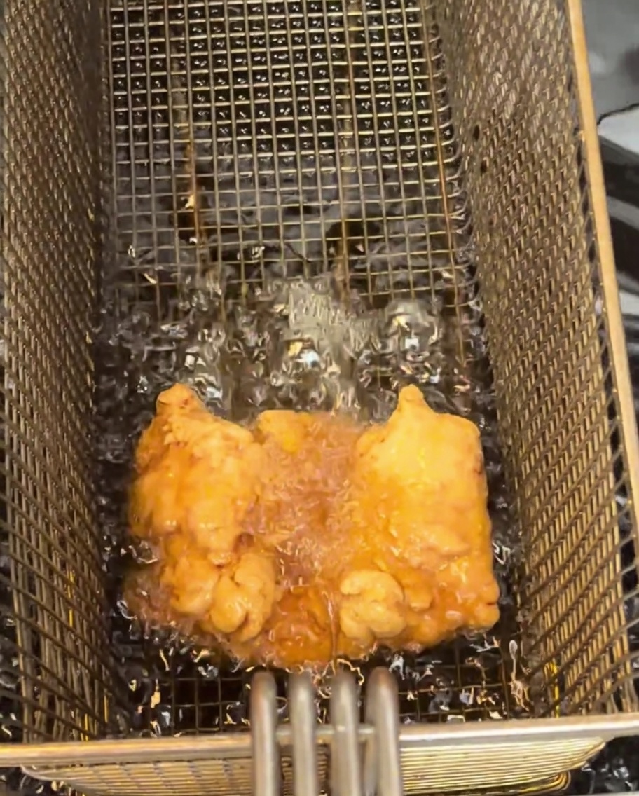 Una coscia di pollo fritta, dorata, che riposa su una griglia di raffreddamento.