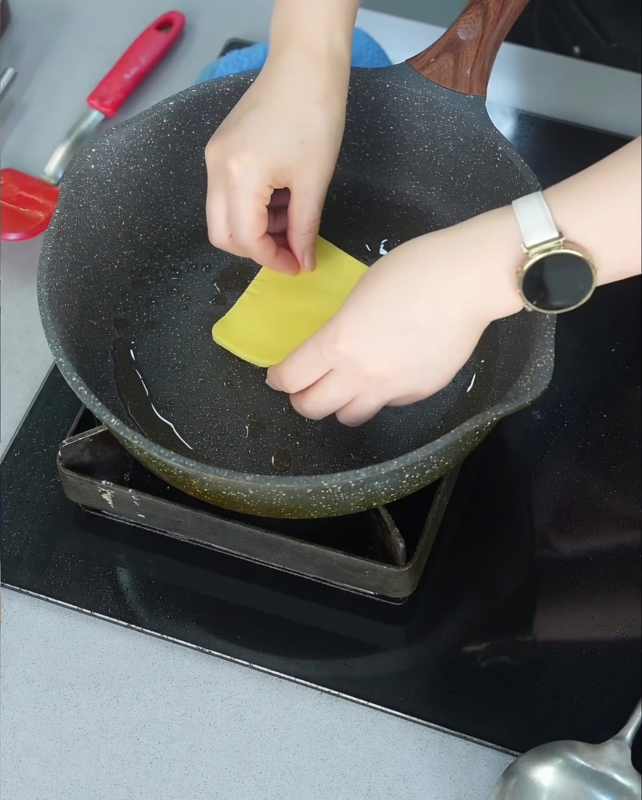 Una fetta di cheddar che si scioglie sopra lhamburger rosolato in padella.
