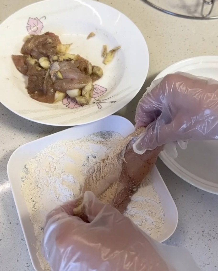 Pezzi di pollo premuti nel mix di panatura su un piatto bianco.