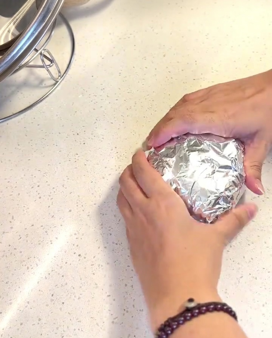 Panini avvolti in carta alluminio lucida allinterno del cestello di una friggitrice ad aria.