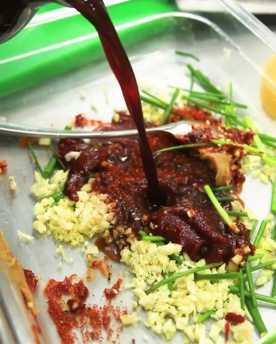 Vino da cucina trasparente versato nella ciotola della marinata, che si mescola con la salsa di soia, i peperoncini e gli aromi.