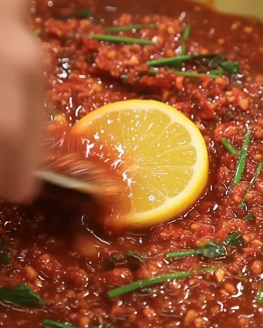Una piccola quantità di olio di sesamo dorato versata al centro del composto della marinata rosso scuro.