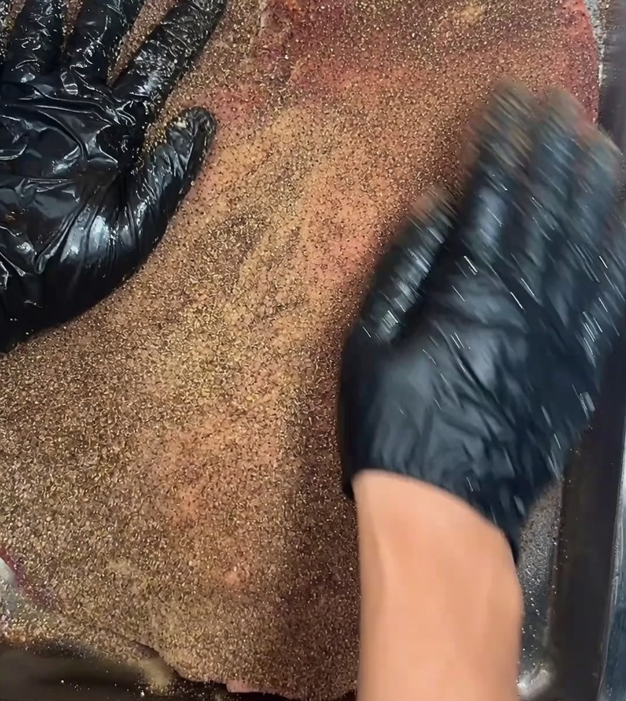 Il brisket condito riposto su una griglia allinterno di un frigorifero per la marinatura.