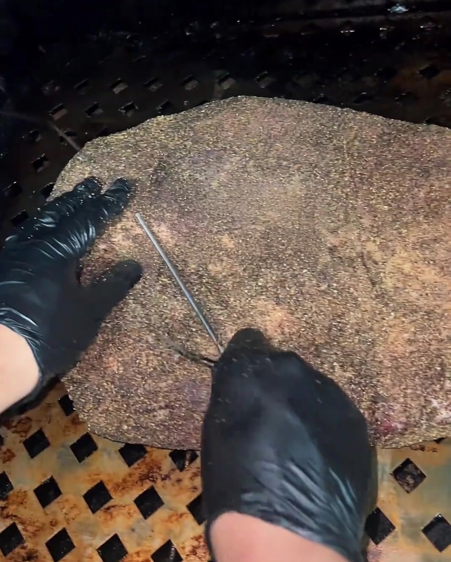 Primo piano di una sonda termometrica inserita nella parte più spessa del brisket crudo.
