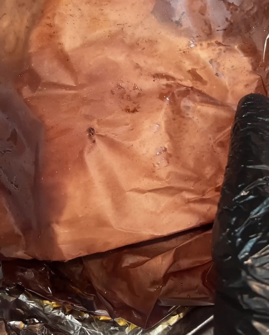 Il brisket cotto scartato, che mostra una crosta scura e umida e ricchi succhi nella carta.
