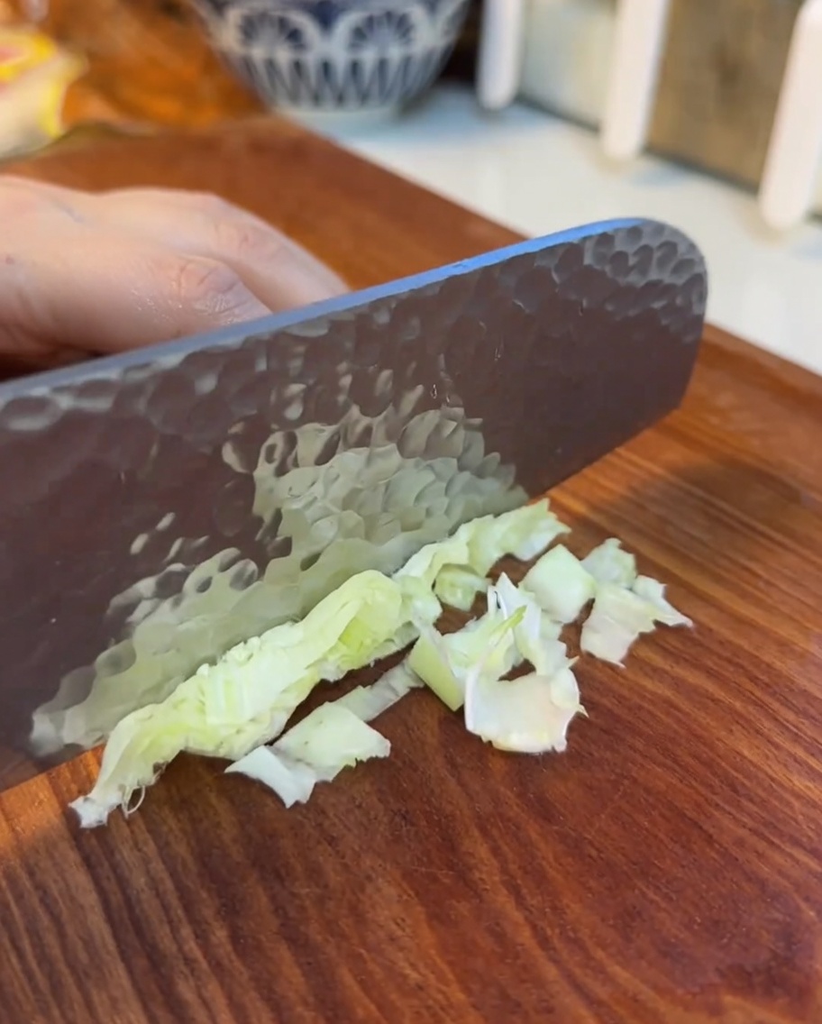 Foglie di lattuga finemente sminuzzate su un tagliere di legno.