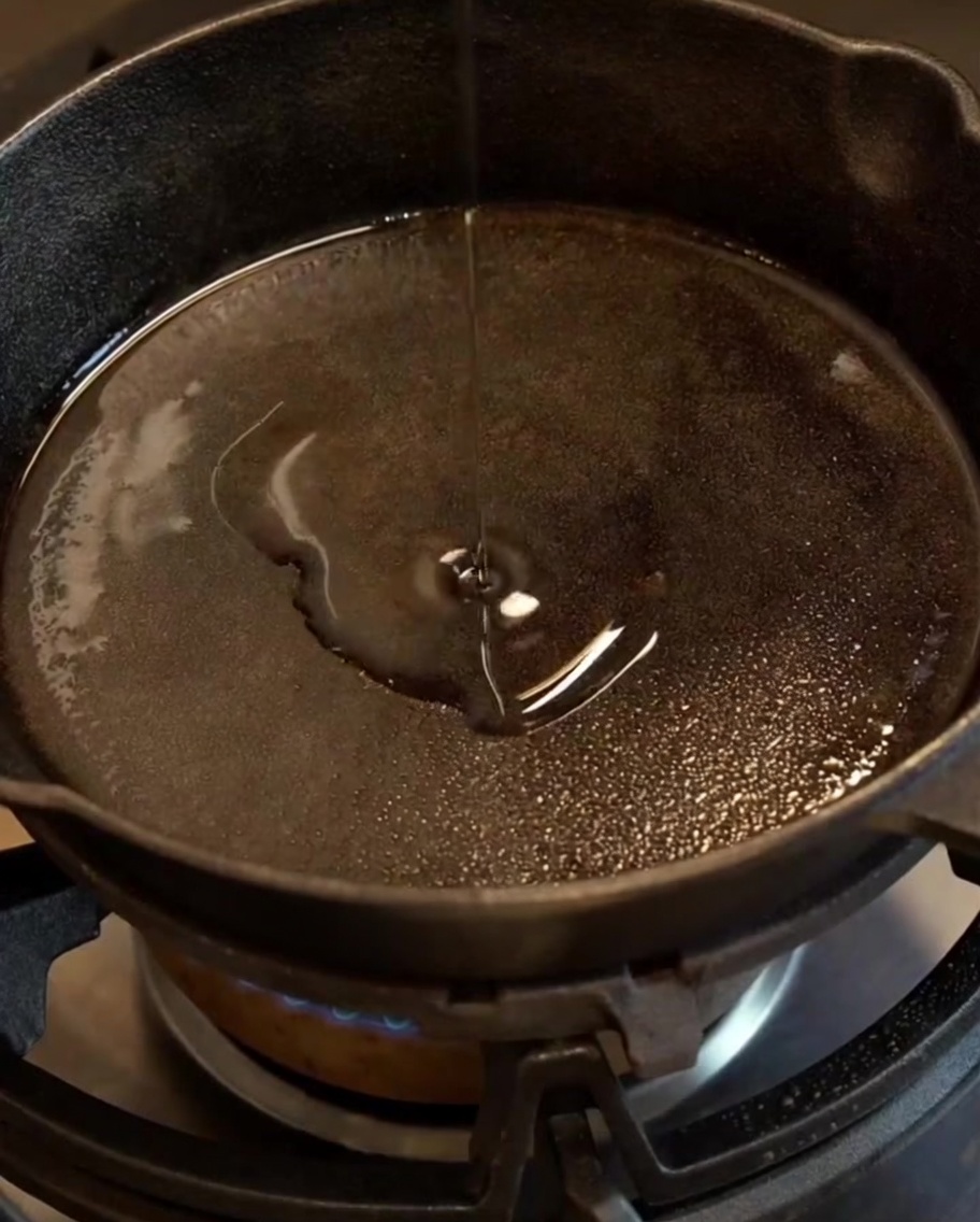 Cipolla e aglio tritati, diventati traslucidi e morbidi, che sfrigolano in una padella in ghisa oliata.