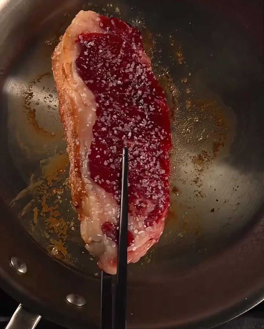 Bistecca in padella irrorata con burro, aglio e rametti di rosmarino fresco.