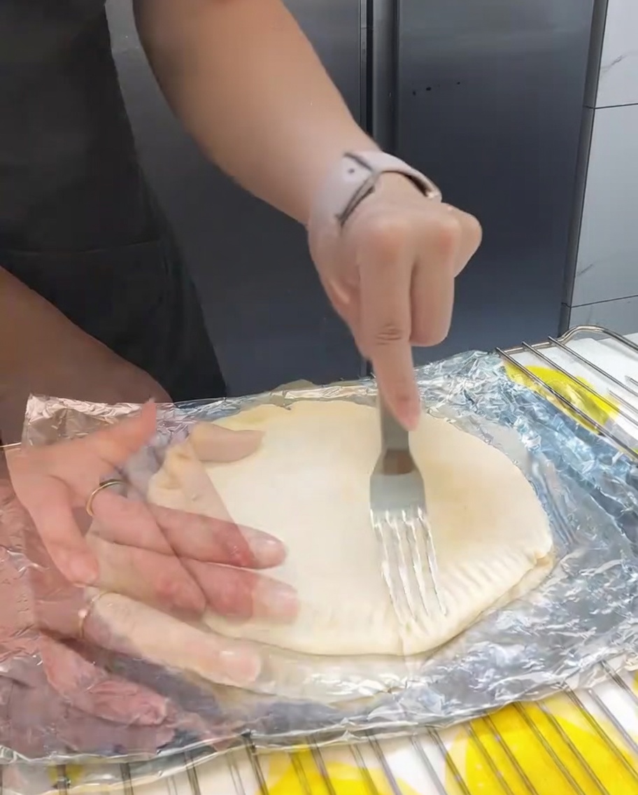 Una forchetta che crimpa i bordi dei pancake sovrapposti per creare una chiusura decorativa e funzionale.