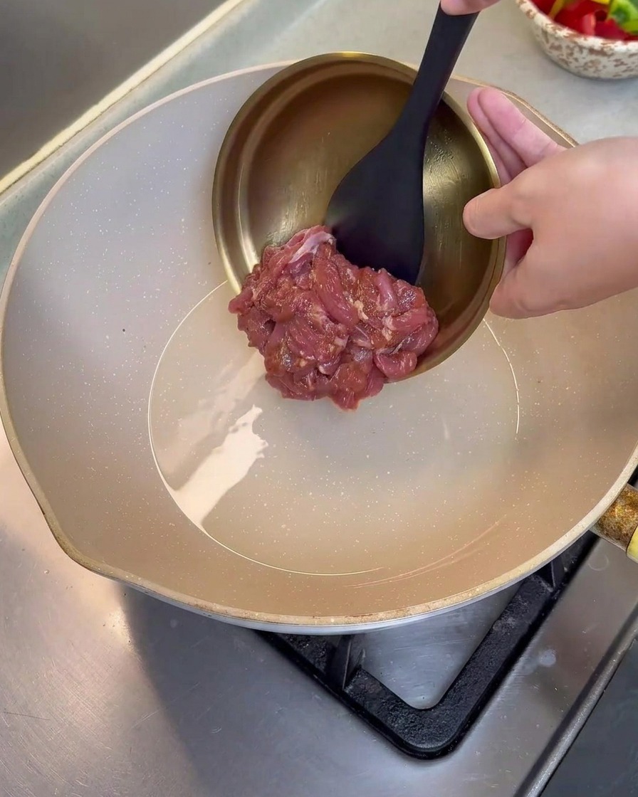 Fette di maiale marinato versate da una ciotola in una padella rovente e leggermente unta.