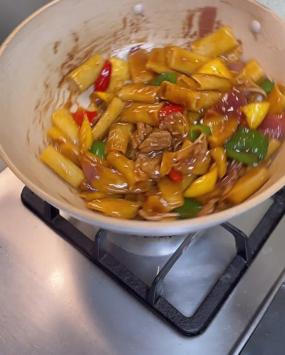 Rigatoni, carne e verdure mescolati insieme nella padella fino ad essere completamente avvolti da una salsa marrone lucida.