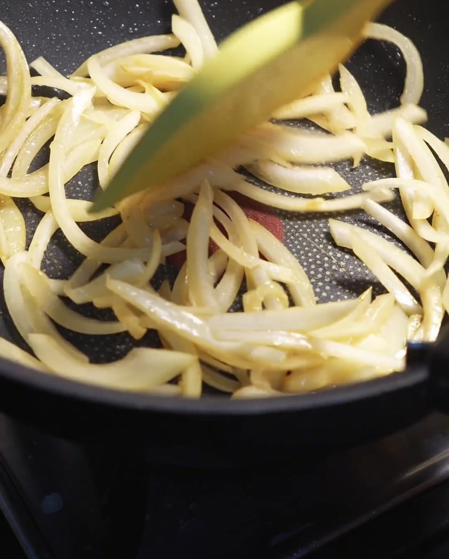 Fette di cipolla bianca saltate in padella con una spatola finché non diventano tenere.