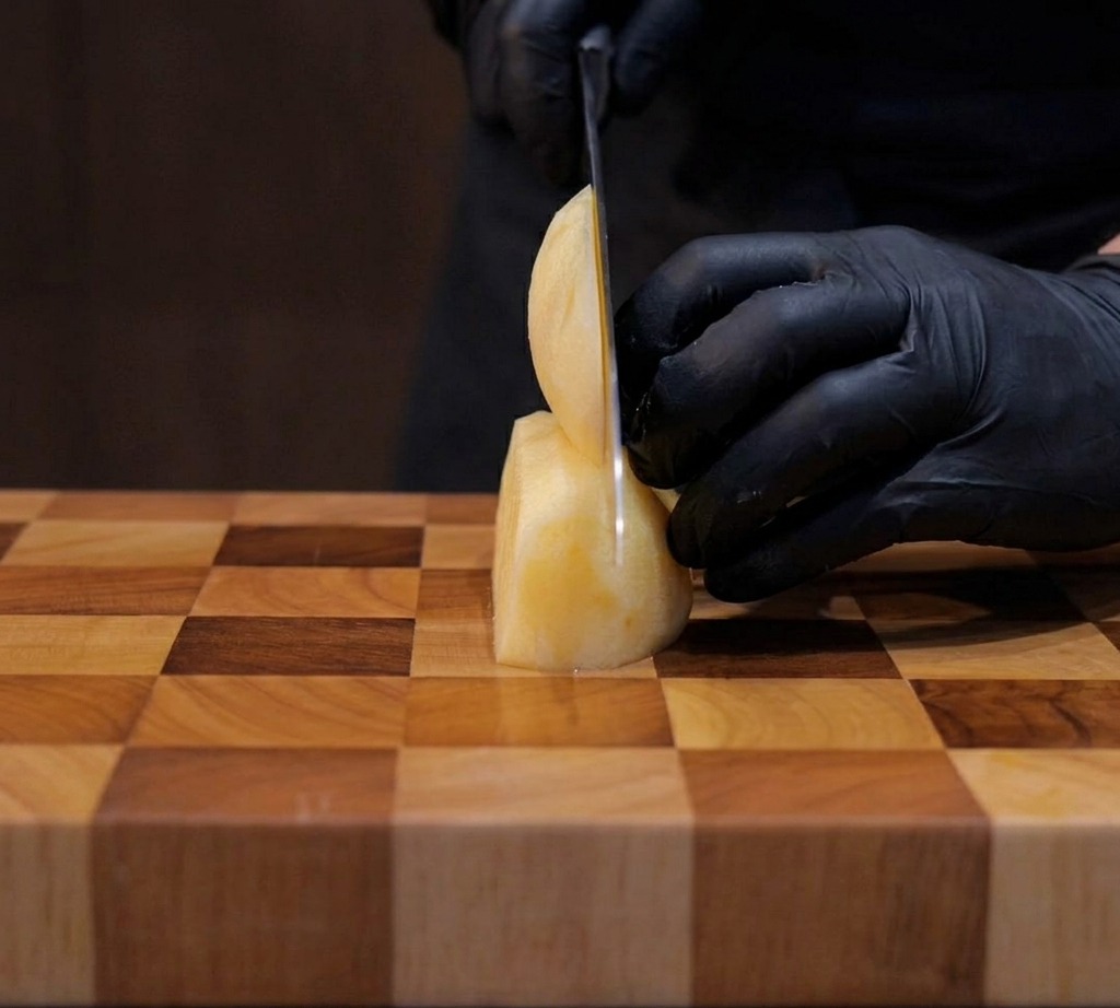 Patate tagliate con cura in cubetti di un centimetro su un tagliere di legno.