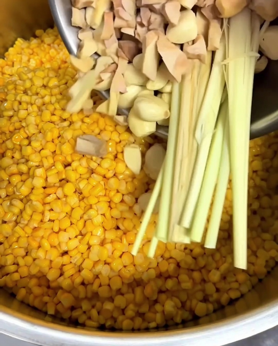 Galangal tritato, spicchi daglio e citronella aggiunti alla pentola.