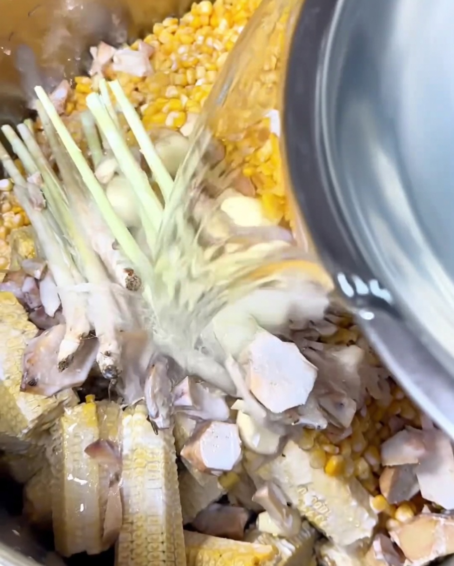 Acqua versata in una pentola con mais, aromi e latte di cocco.
