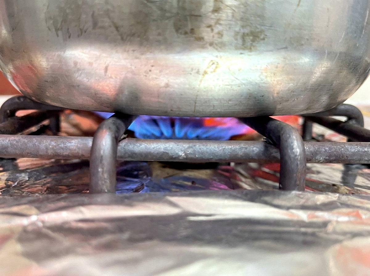 Pentola su un fornello a gas con fiamma blu.