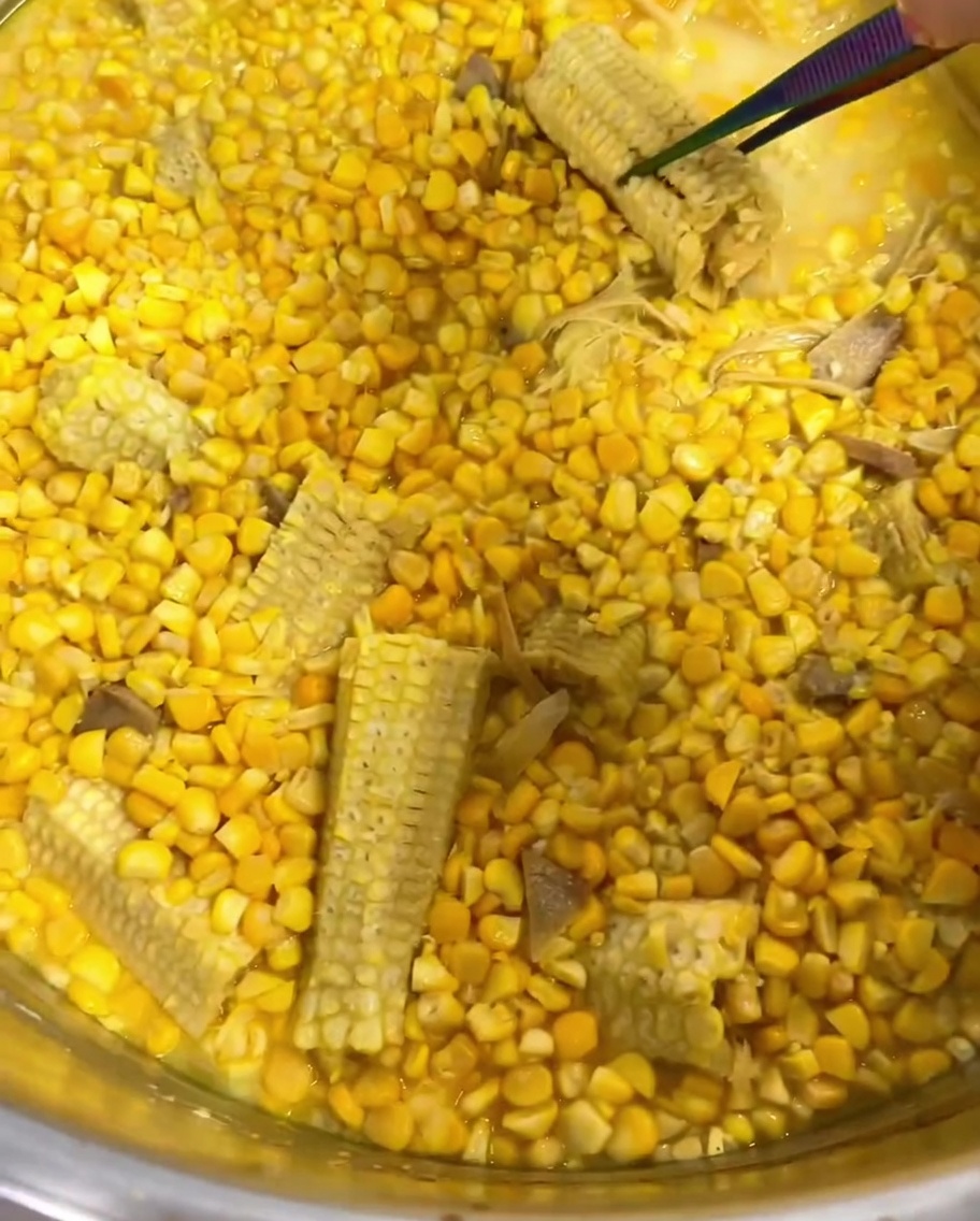 Pinze che rimuovono la citronella e una pannocchia dalla zuppa.