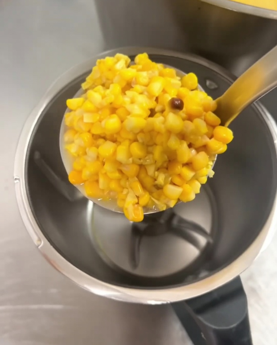 Chicchi di mais cotti aggiunti a un frullatore capiente.