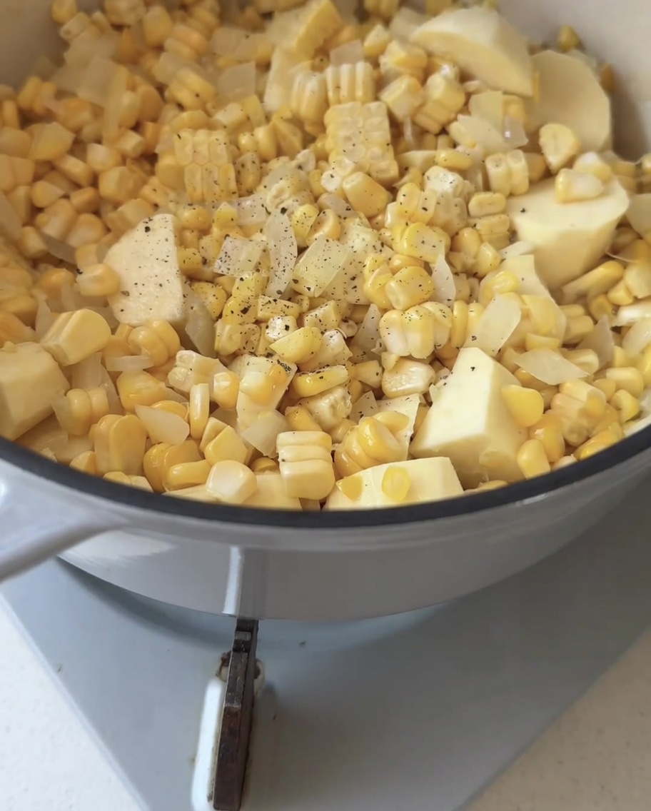 Pepe nero macinato fresco sopra un mix di mais, cipolla e patata dolce in una pentola di cottura.