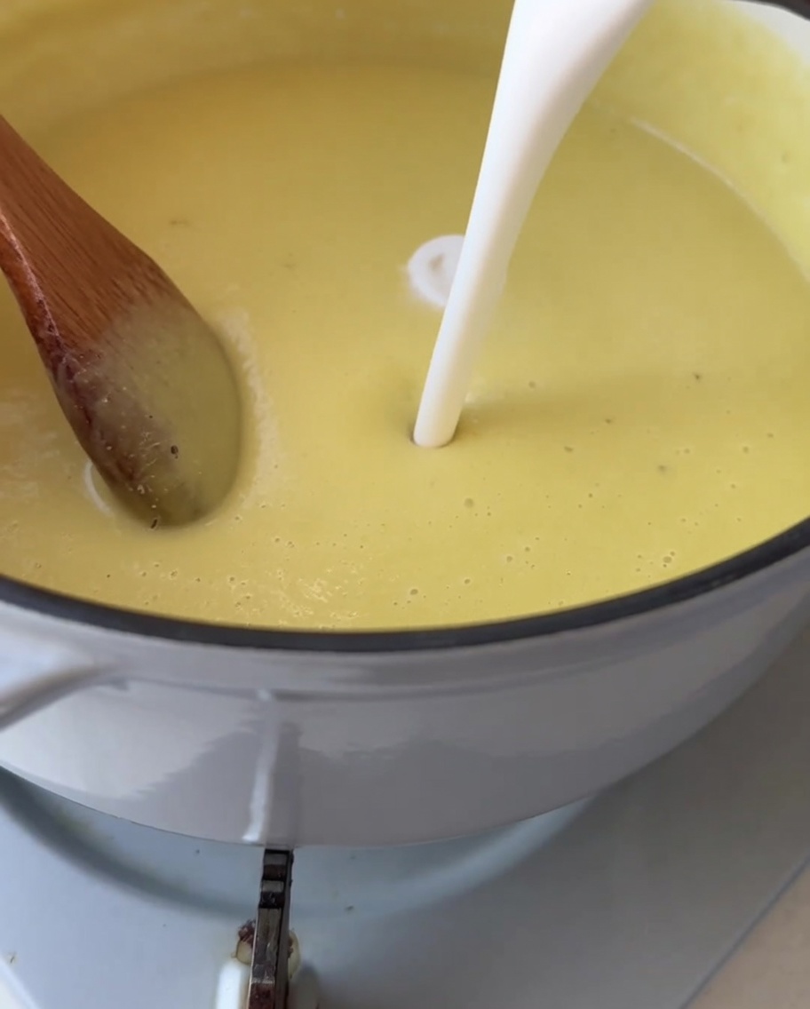 Panna bianca versata in una pentola di vellutata di mais liscia e giallo brillante.