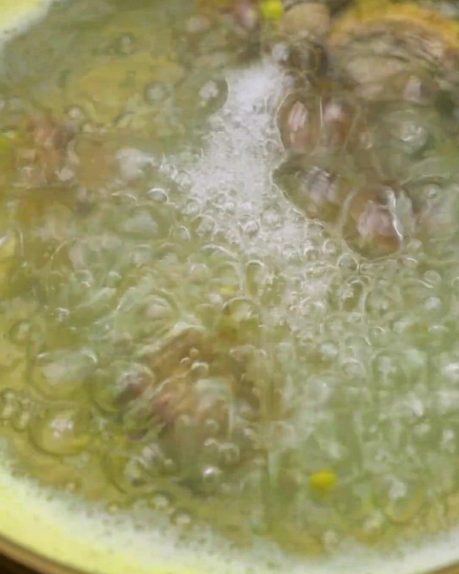Le vongole vengono aggiunte in una pentola di acqua di mais bollente utilizzando un colino a rete.