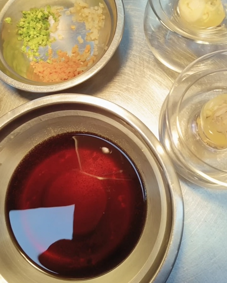 Vista ravvicinata di piccoli contenitori di metallo contenenti aglio tritato, coriandolo tritato e carote a dadini, pronti per guarnire la gelatina.