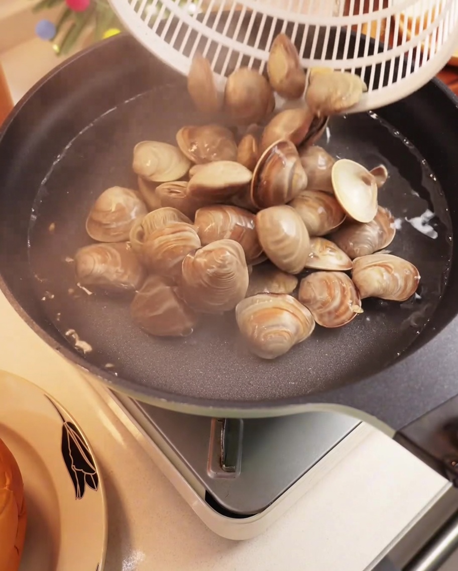 Vongole fresche che bollono in una pentola dacqua, i gusci si aprono.