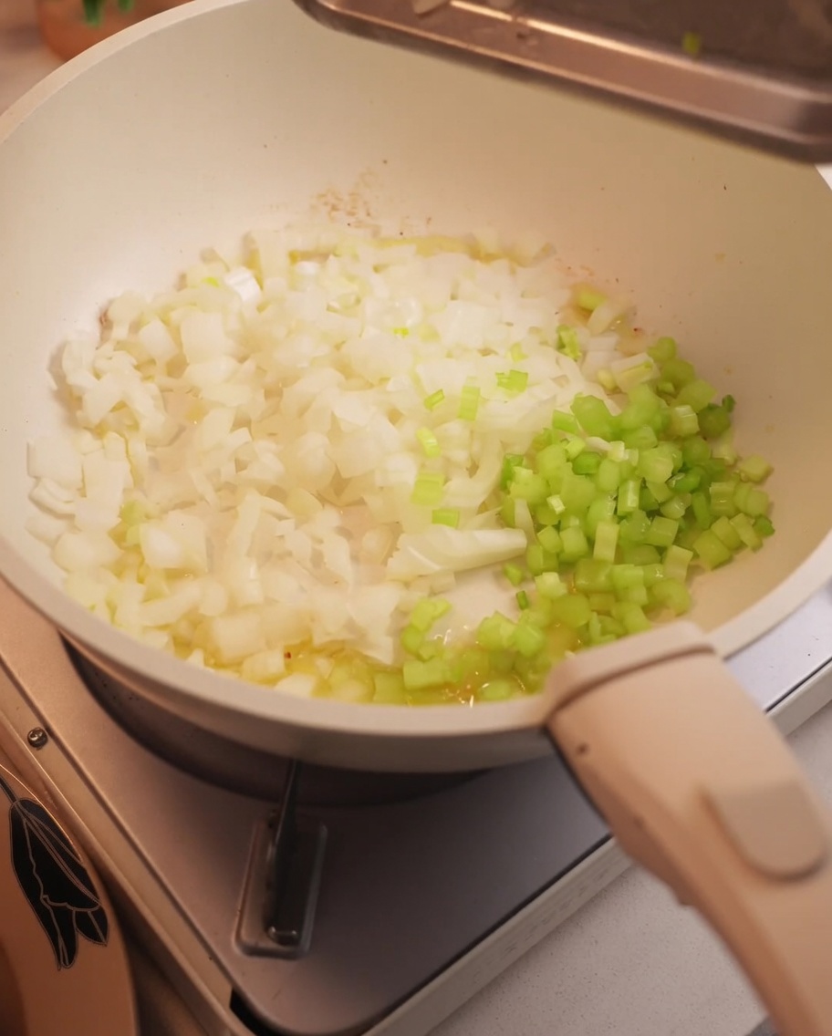 Cipolle e sedano tritati che soffriggono in padella.