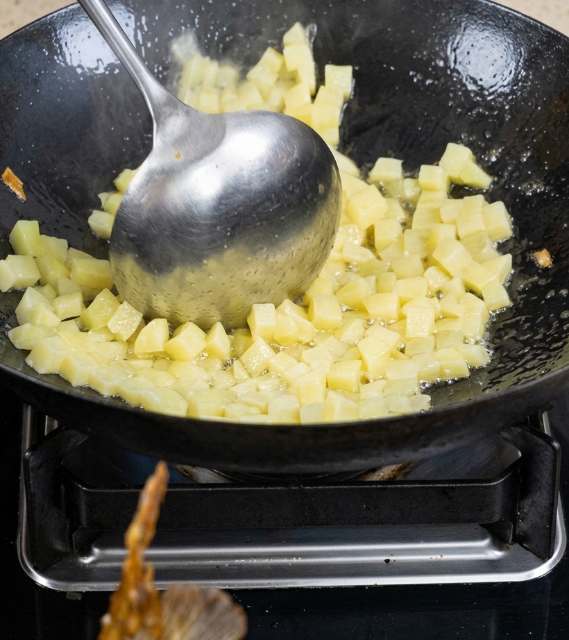 Patate a cubetti saltate in un wok con olio finché non sono leggermente dorate.