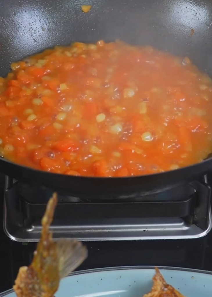 Acqua bollente versata in un wok contenente patate e pomodori cotti.