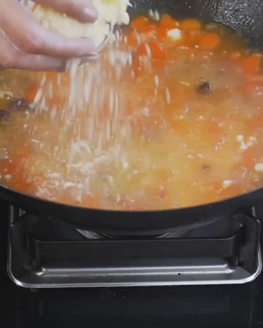 Gnocchetti di farina e uova spolverati in una pentola di zuppa in ebollizione con pomodori e patate.
