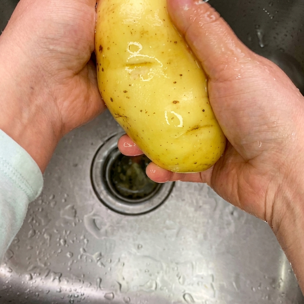 Sottili listarelle di patate crude su un tagliere di legno pulito.