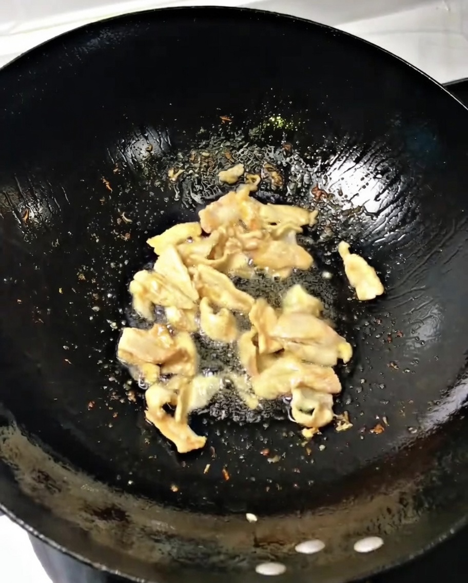 Cipollotti tritati e zenzero mescolati al maiale in un wok ben caldo.
