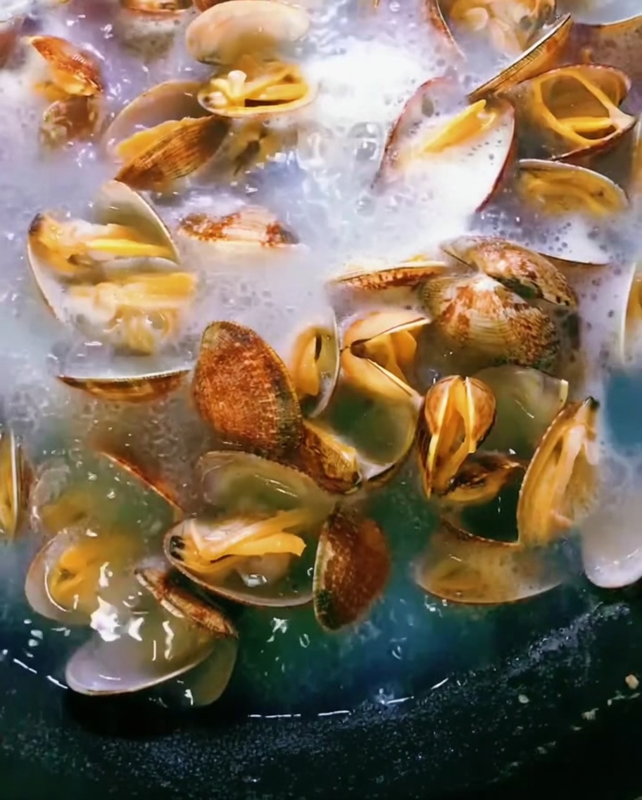 Vongole in una pentola di acqua bollente, i gusci si aprono mentre cuociono.