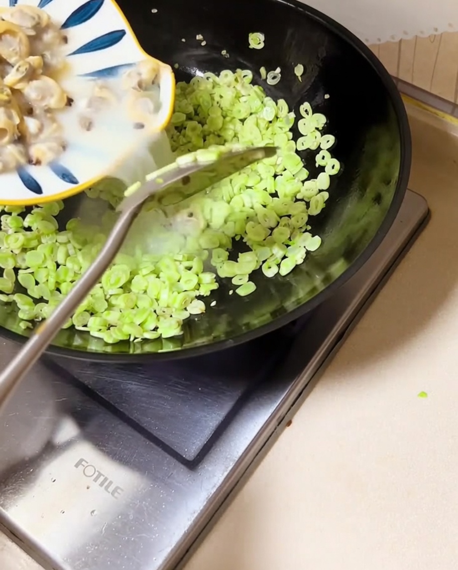 Le vongole e il loro brodo versati nel wok con i fagioli.
