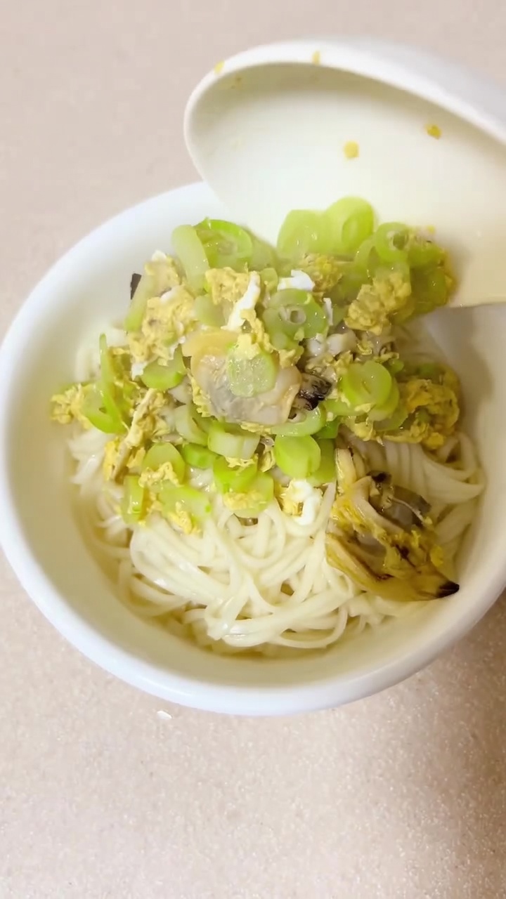 Una ciotola fumante di zuppa di noodle con vongole e fagioli, arricchita da morbidi nastri di uovo.