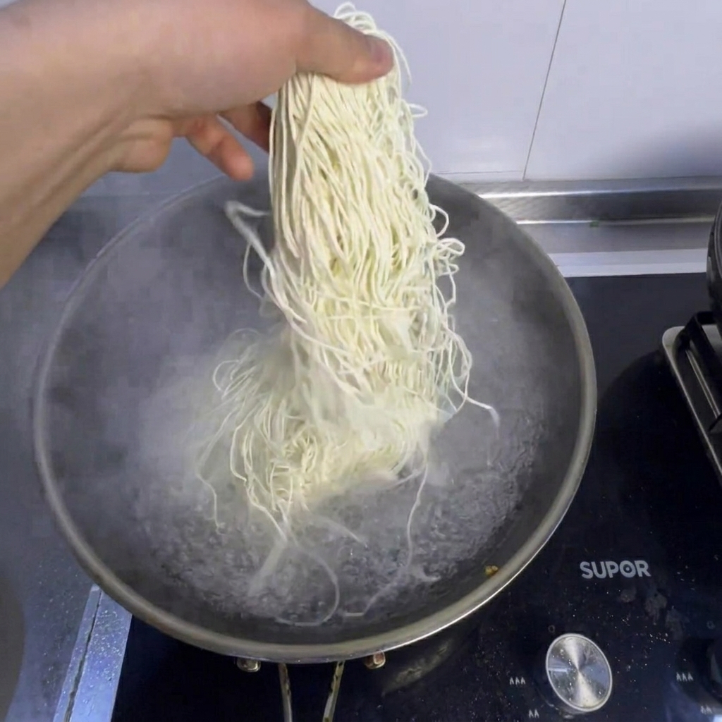 Noodles e bok choy fresco cotti in una pentola di acqua bollente.